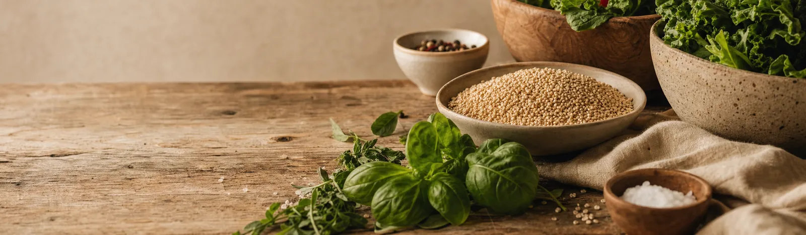 Basilic, origan, un bol de quinoa et des bols de chou frisé posés sur un plan de travail en bois usé